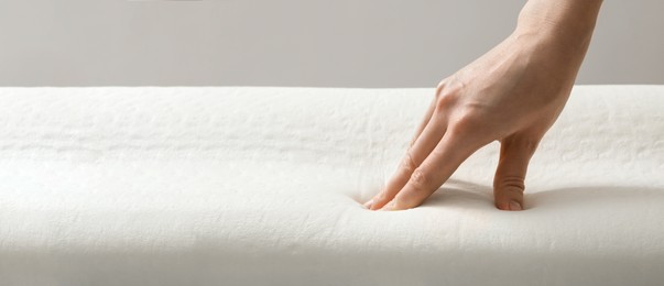 Woman touching memory foam pillow, closeup. Banner design with space for text