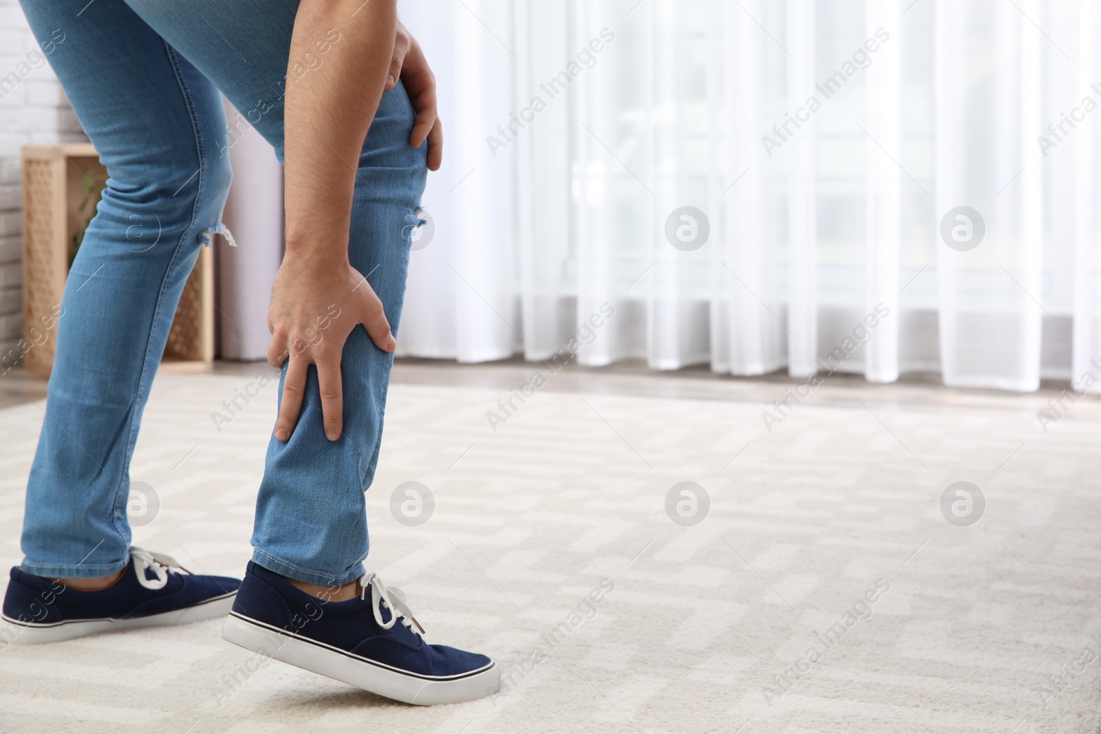 Photo of Man suffering from leg pain at home, closeup. Space for text