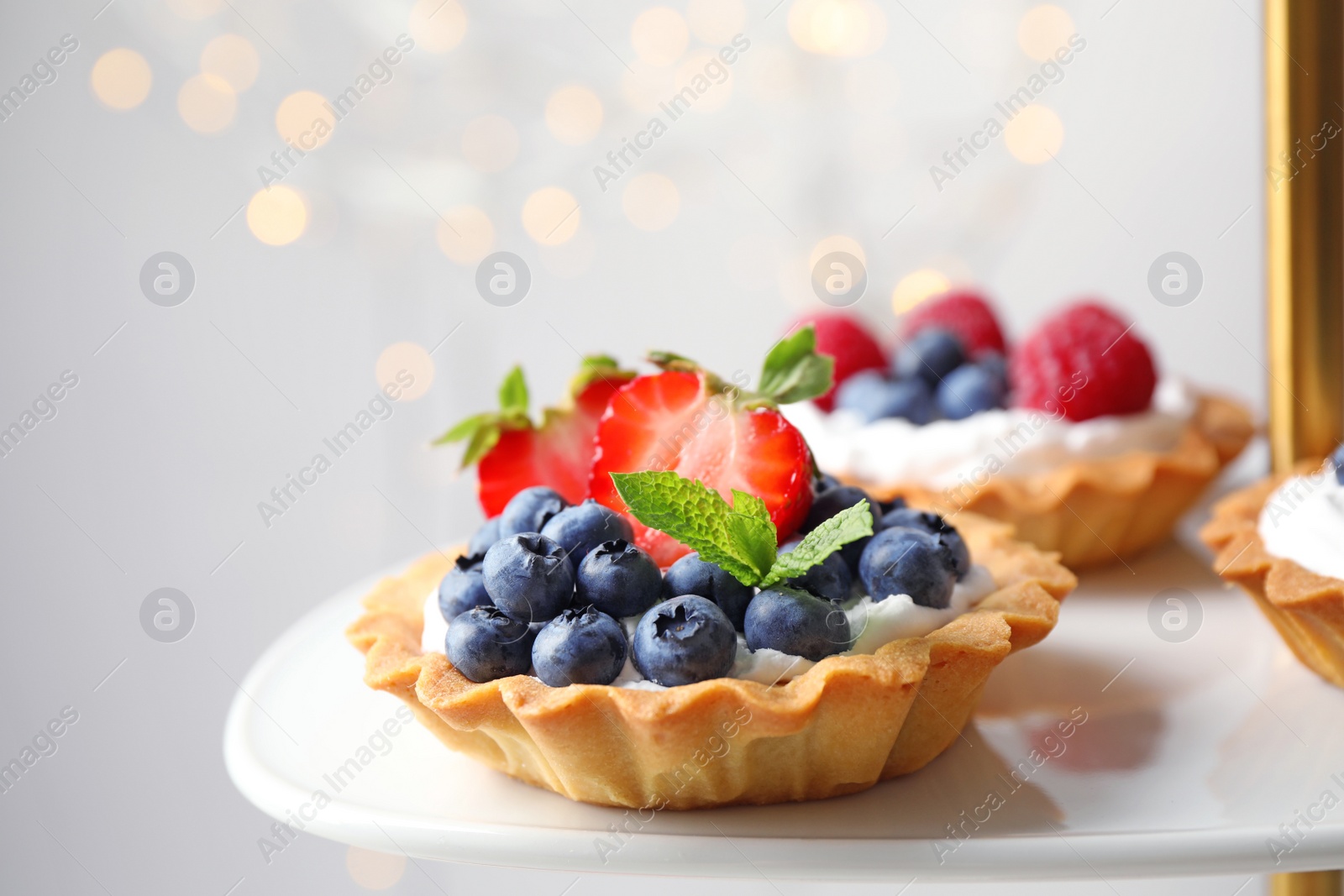 Photo of Tarts with different berries on cake stand. Delicious pastries