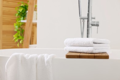 Photo of Fresh white towels on tub in bathroom