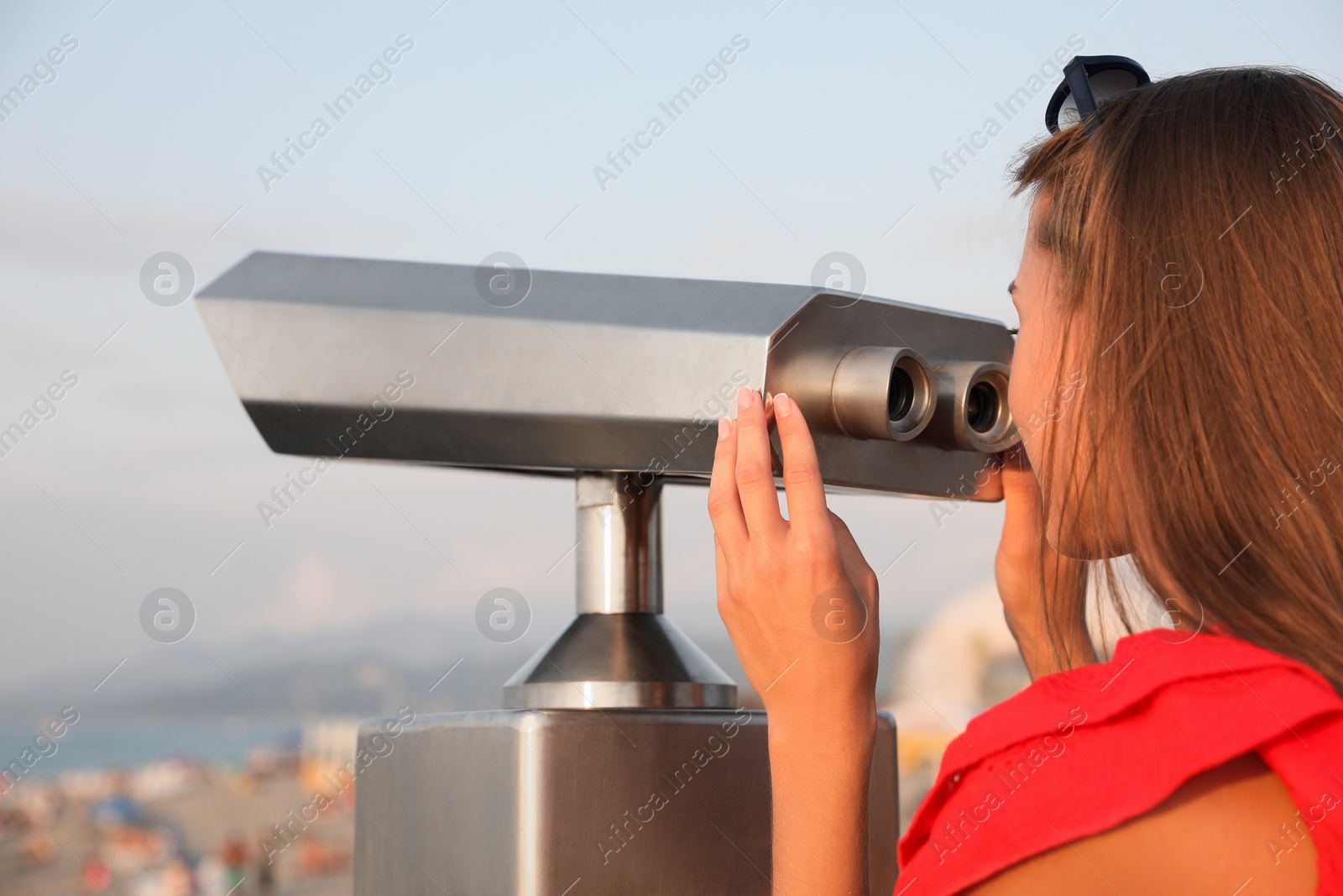 Photo of Young woman looking through tourist viewing machine at observation deck