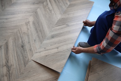 Worker installing laminated wooden floor indoors, closeup