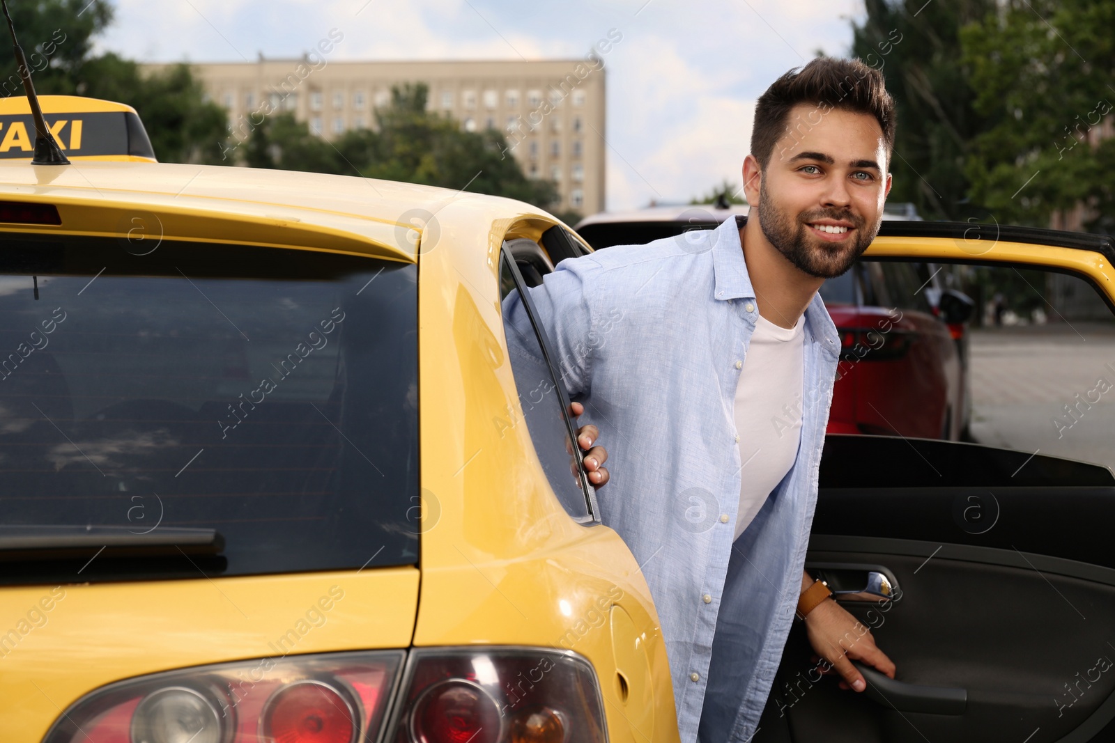 Photo of Handsome young man getting out of taxi on city street