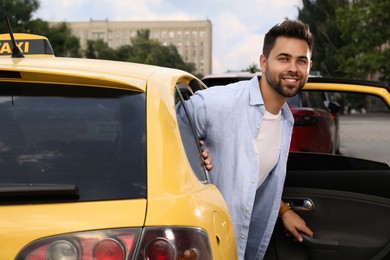 Photo of Handsome young man getting out of taxi on city street