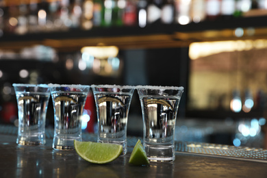 Photo of Mexican Tequila shots with lime slices on bar counter