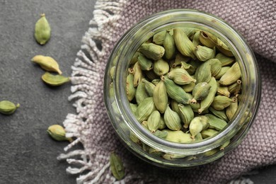 Photo of Jar with dry cardamom pods on dark grey table, top view