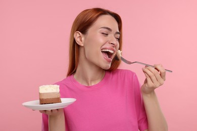 Photo of Young woman eating piece of tasty cake on pink background