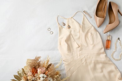 Photo of Stylish dress with elegant bijouterie, shoes and bouquet on white fabric, flat lay. Space for text