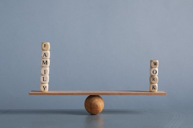 Photo of Work family balance concept. Wooden ball with cubes and small plank on grey background