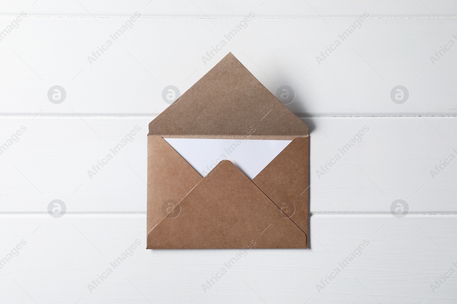 Photo of Letter envelope with card on white wooden table, top view