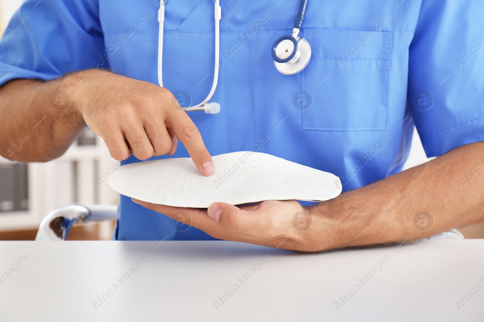 Photo of Male orthopedist showing insole in clinic, closeup