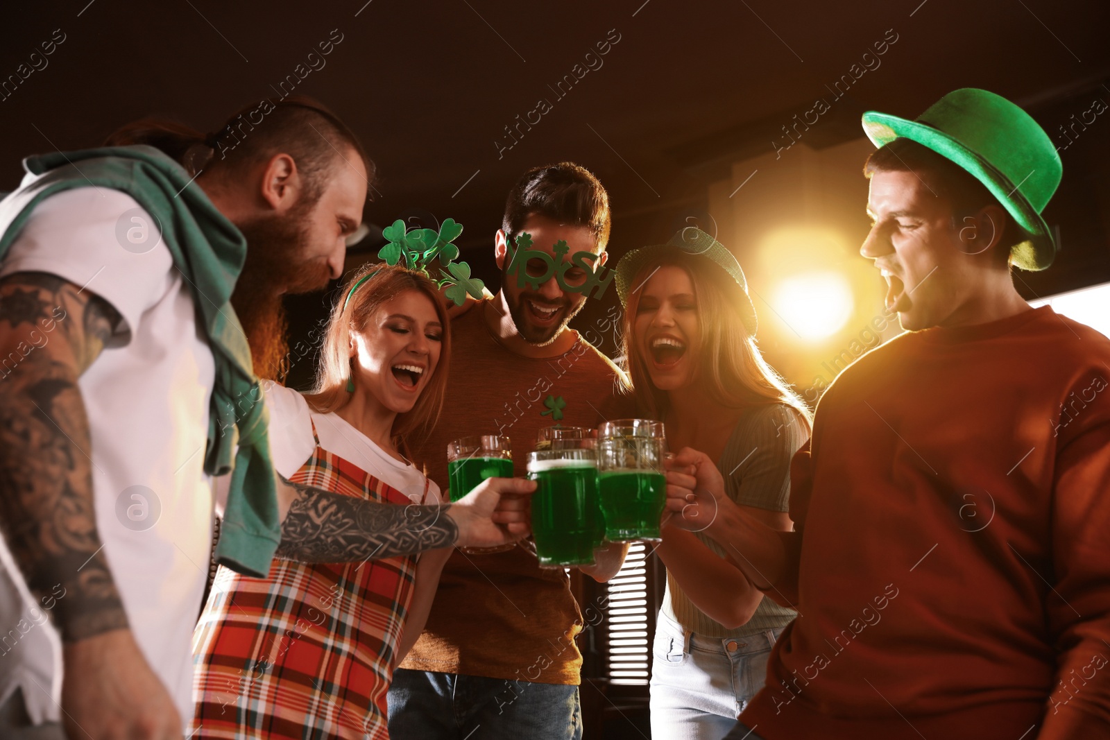 Photo of Group of friends toasting with green beer in pub, low angle view. St. Patrick's Day celebration