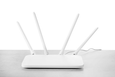 Photo of New modern Wi-Fi router on grey table against white background