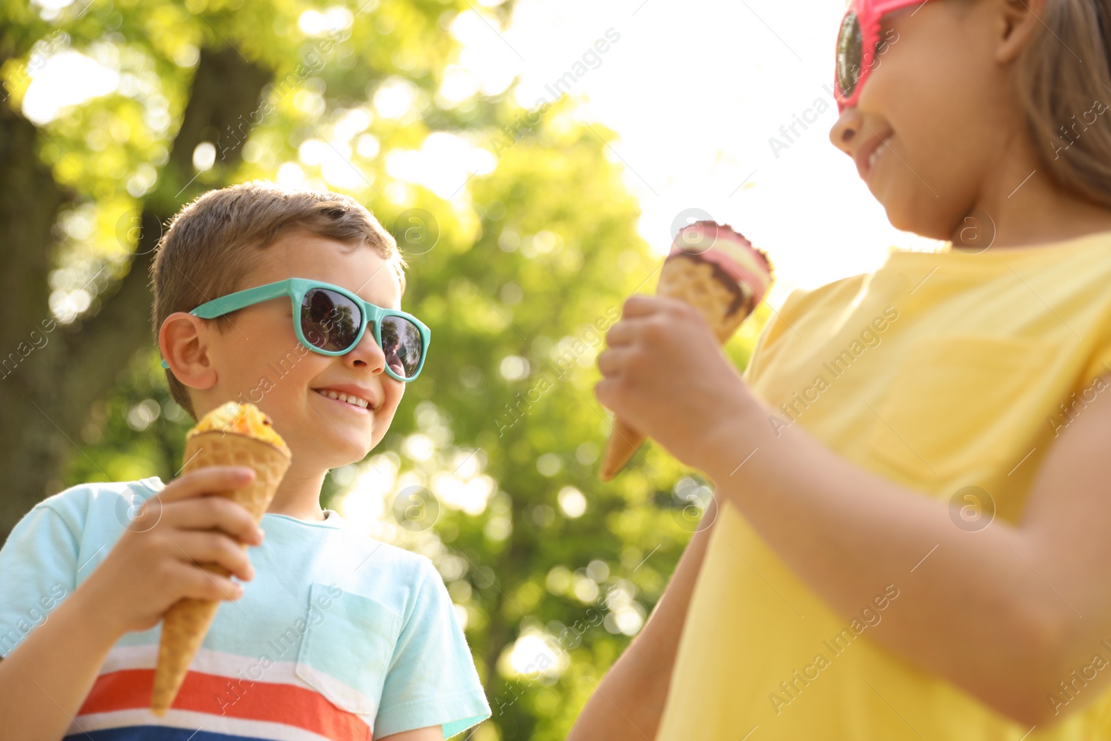 Photo of Cute little children with delicious ice creams outdoors, low angle view