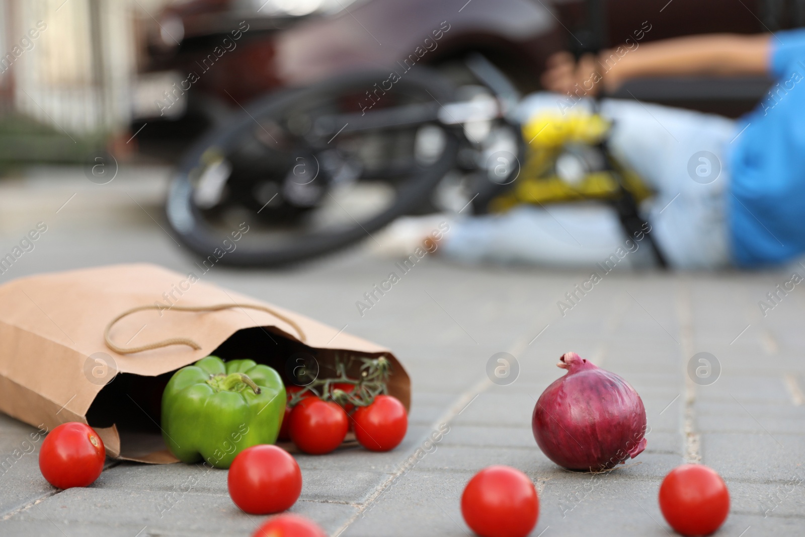Photo of Woman fallen from bicycle after car accident outdoors, focus on scattered vegetables