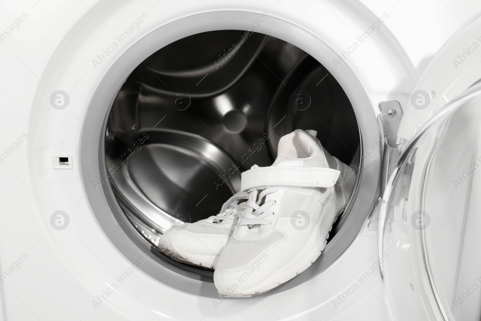 Photo of Stylish clean sneakers inside modern washing machine