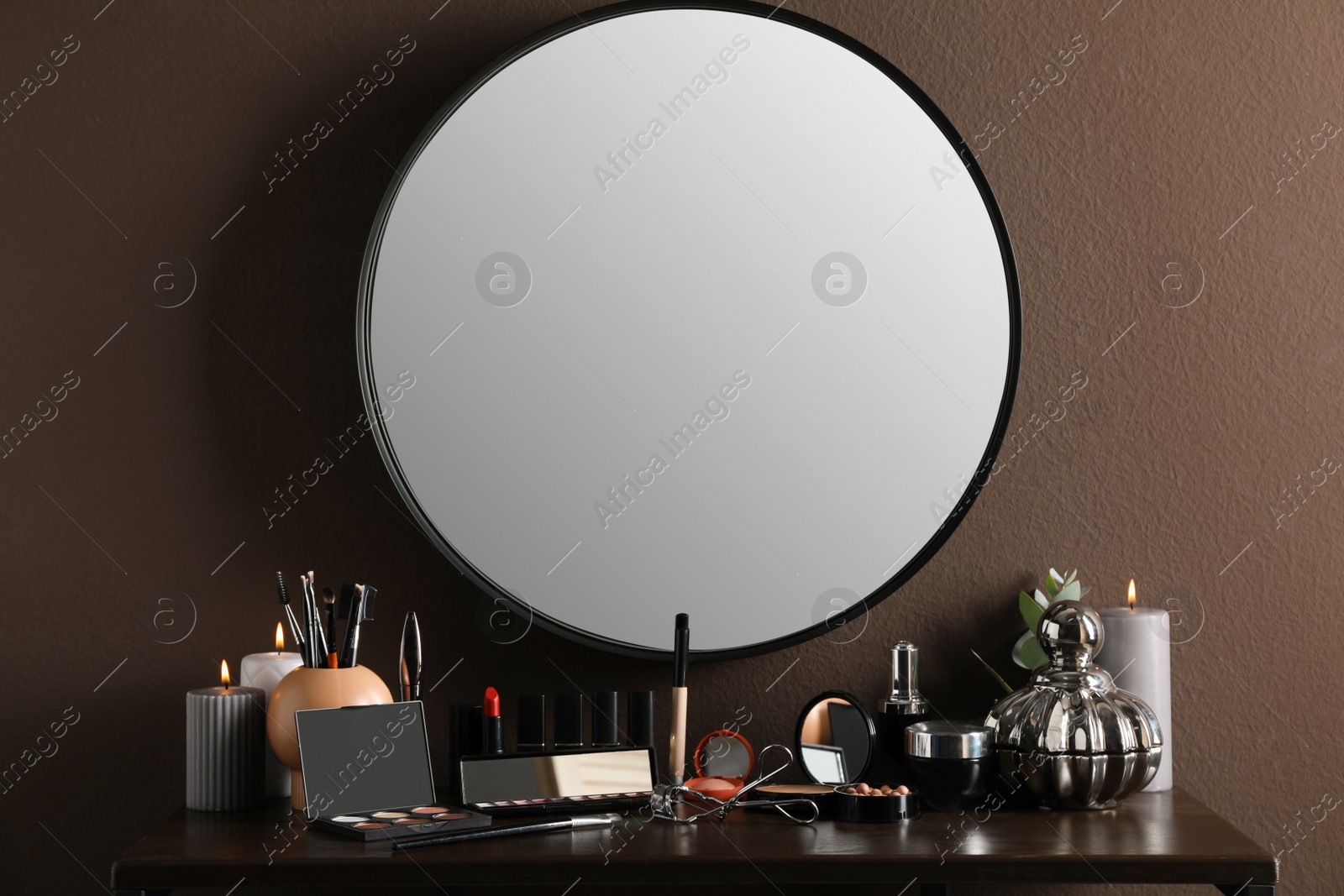 Photo of Stylish round mirror hanging above dressing table with cosmetic products