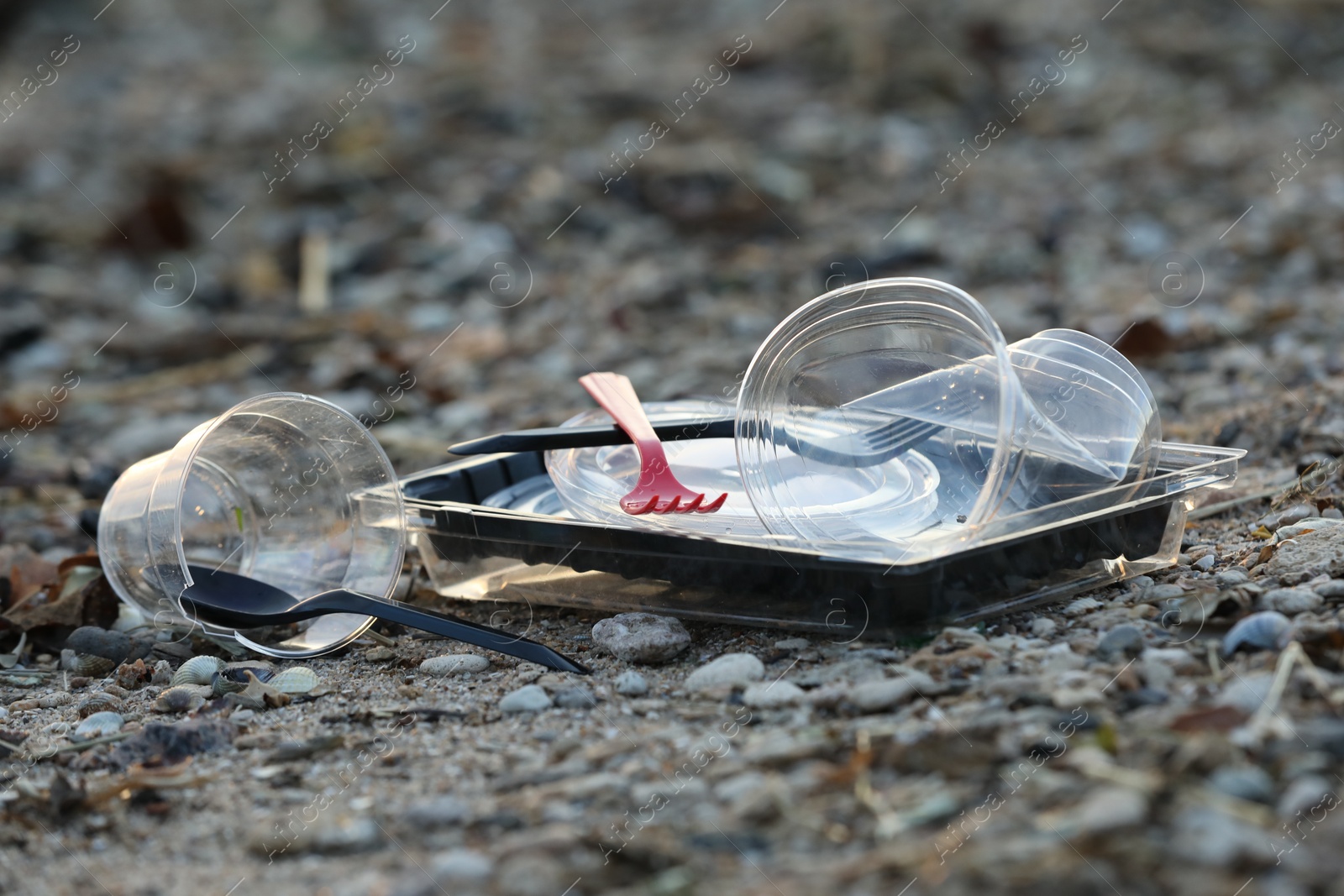 Photo of Used plastic tableware at beach, space for text. Environmental pollution concept