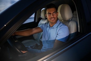 Photo of Handsome man in his modern car, view from outside