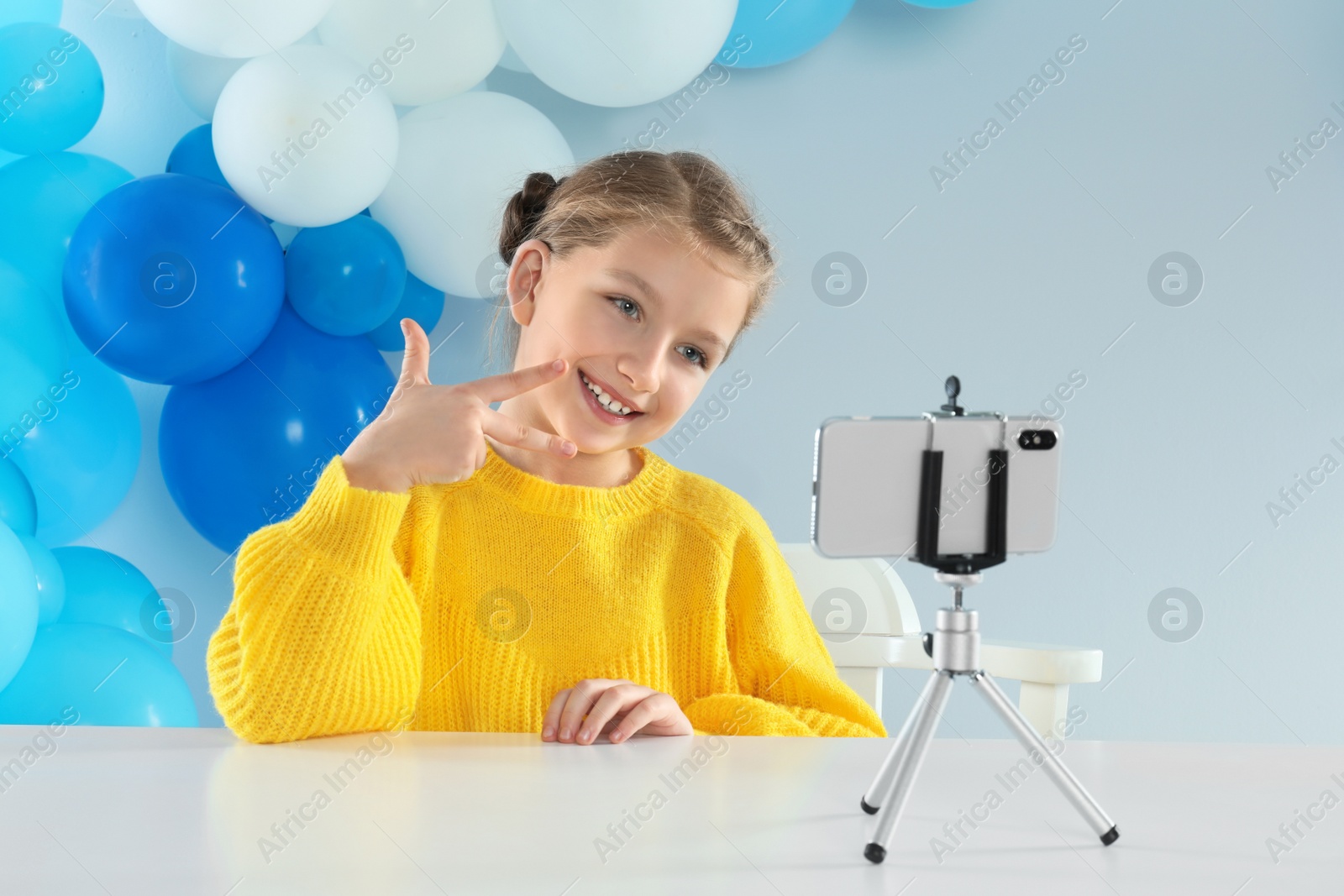 Photo of Cute little blogger recording video at table