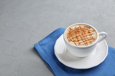 Cup of tasty caramel macchiato on table. Space for text