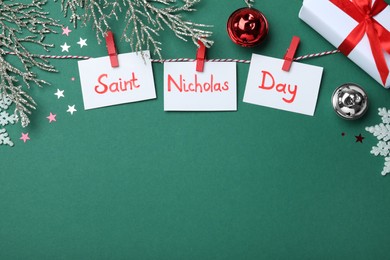 Photo of Paper notes with words Saint Nicholas Day and festive decor on green background, flat lay. Space for text