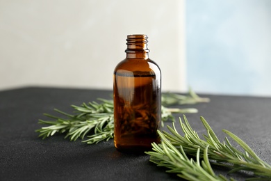 Bottle with rosemary essential oil on table