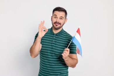Photo of Man with flag of Netherlands showing ok gesture on white background