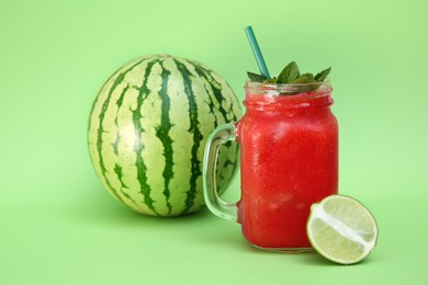 Photo of Glass of delicious watermelon drink with mint and fresh fruits on light green background