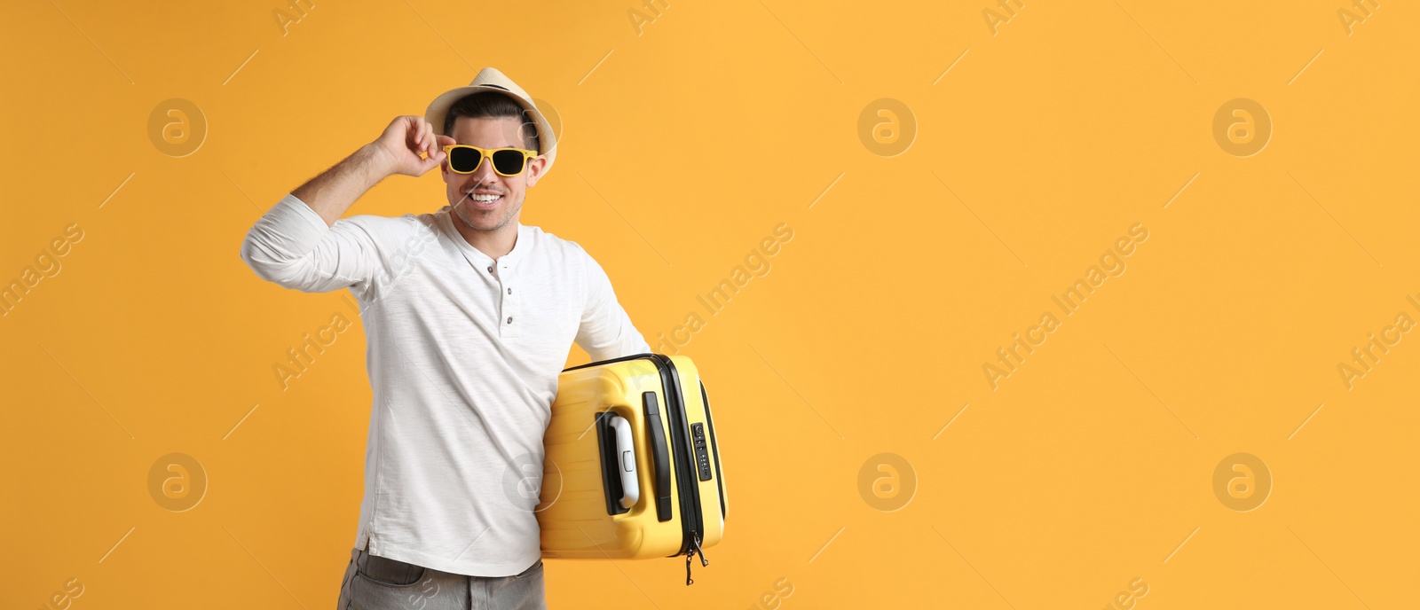 Photo of Male tourist with suitcase on yellow background