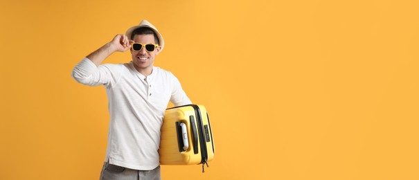 Male tourist with suitcase on yellow background