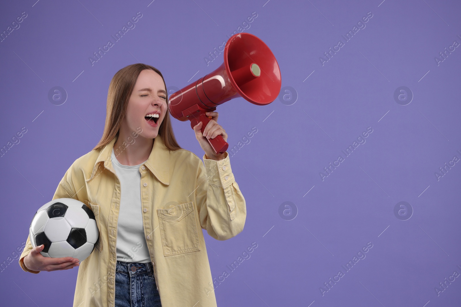 Photo of Emotional sports fan with ball and megaphone on purple background. Space for text