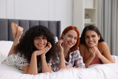 Photo of Happy young friends on bed at home