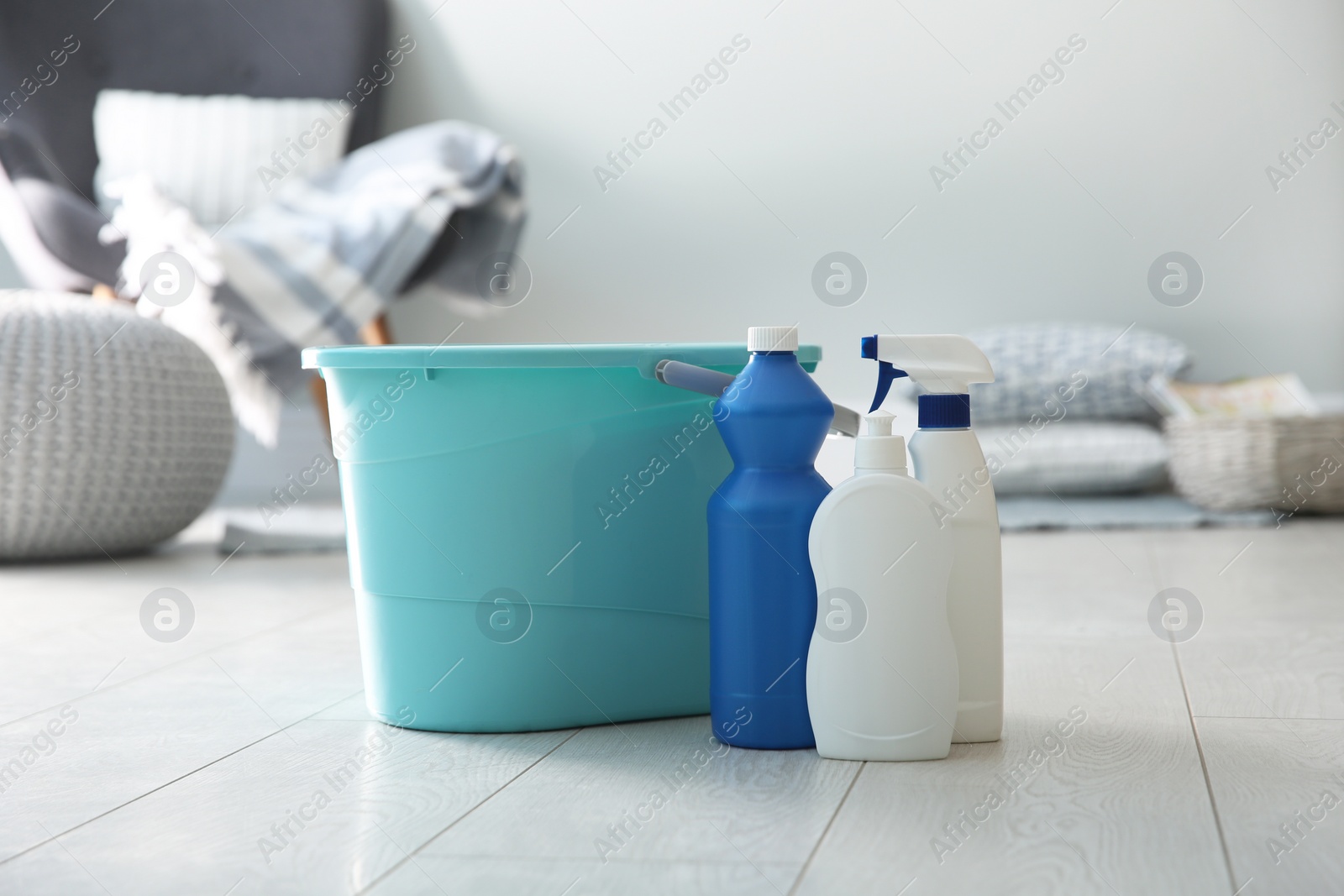 Photo of Bucket and different cleaning products on floor indoors