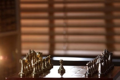 Chessboard with game pieces near window indoors, space for text