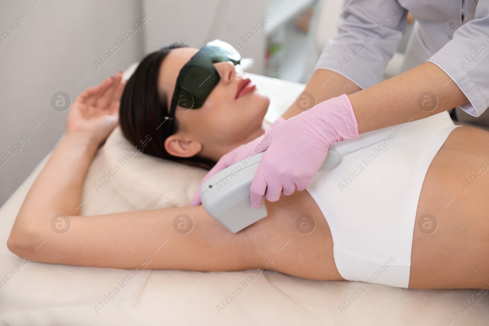 Photo of Young woman undergoing laser epilation procedure in beauty salon