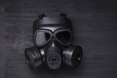 Photo of One gas mask on black wooden background, top view