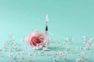 Photo of Cosmetology. Medical syringe, rose and gypsophila flowers on turquoise background