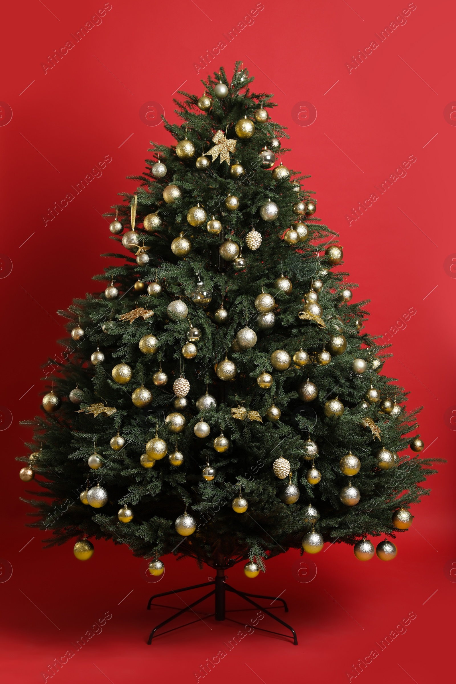 Photo of Beautifully decorated Christmas tree on red background