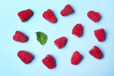 Flat lay composition with delicious ripe raspberries on blue background