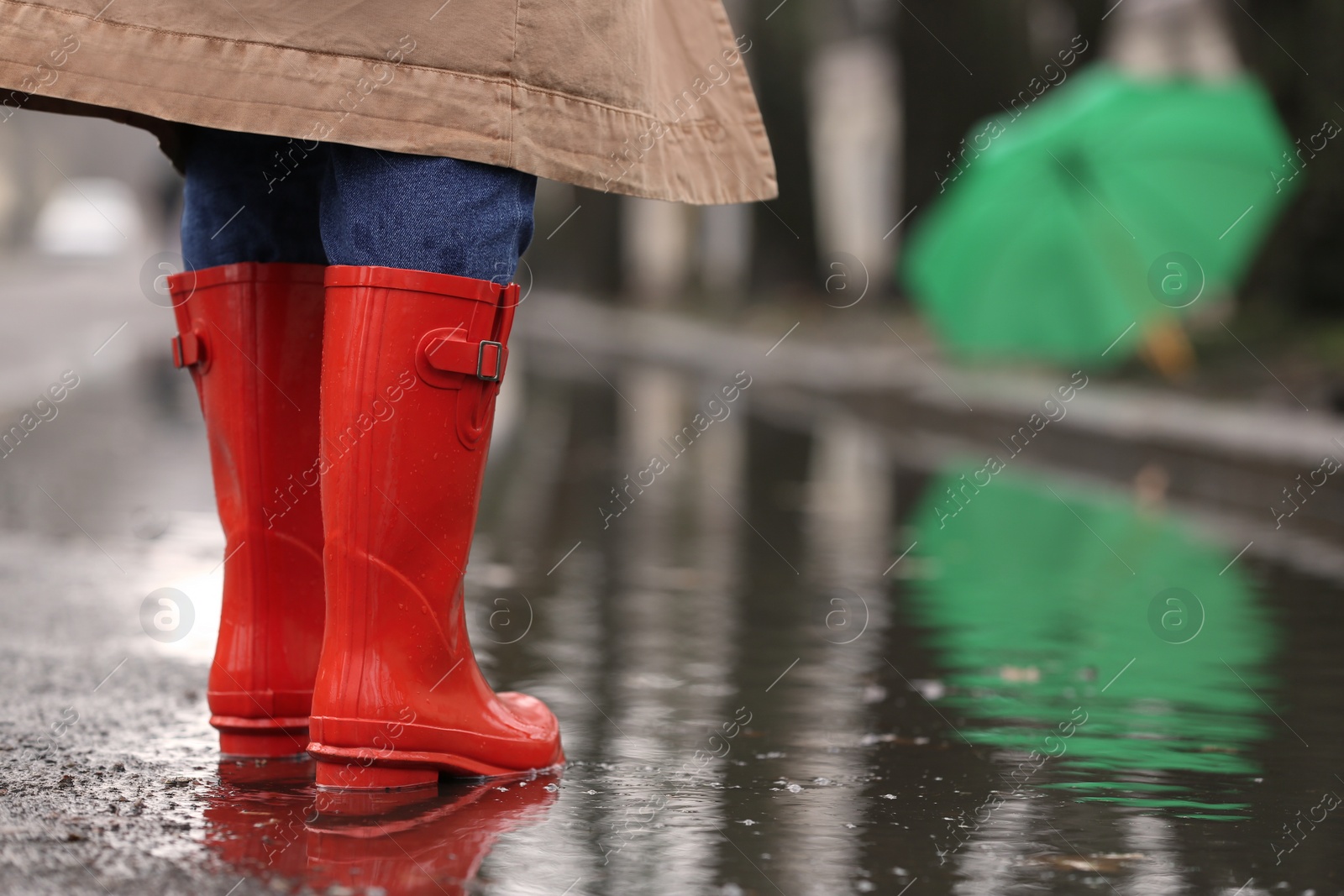 Photo of Woman in rubber boots walking outdoors on rainy day, closeup. Space for text