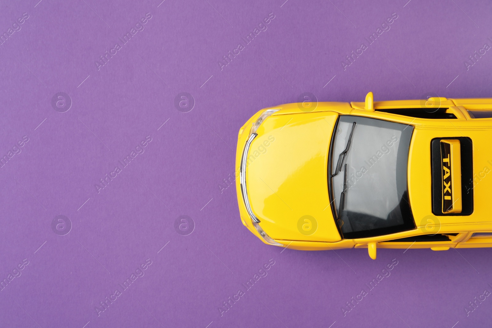 Photo of Yellow taxi car model on purple background, top view. Space for text
