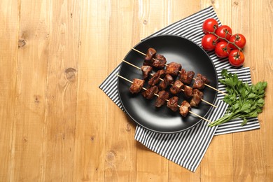 Delicious shish kebabs with vegetables on wooden table, flat lay. Space for text