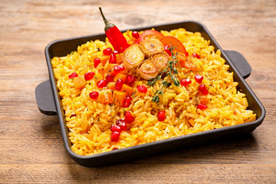 Photo of Tasty rice pilaf with vegetables on wooden table