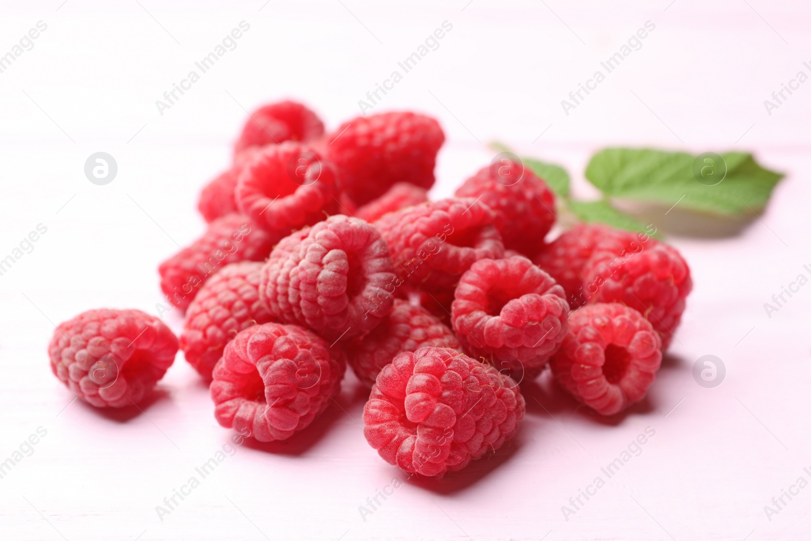 Photo of Delicious fresh ripe raspberries on pink wooden table, closeup view