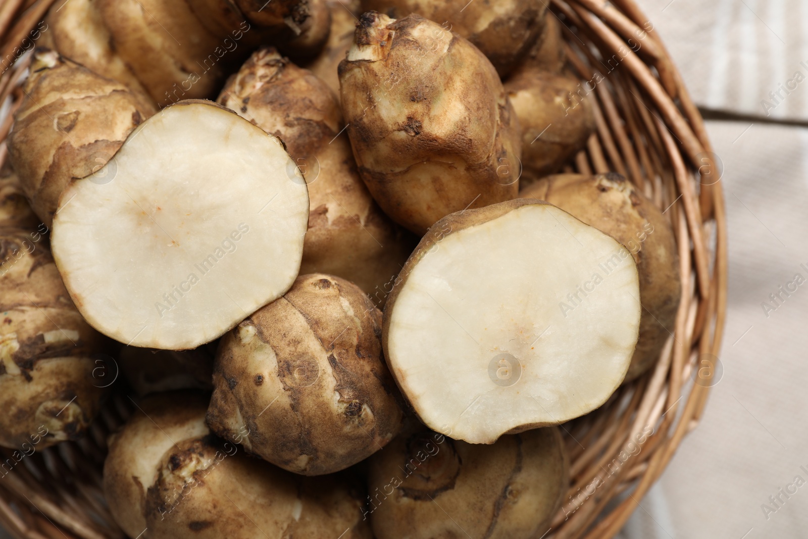 Photo of Wicker basket with many Jerusalem artichokes, closeup