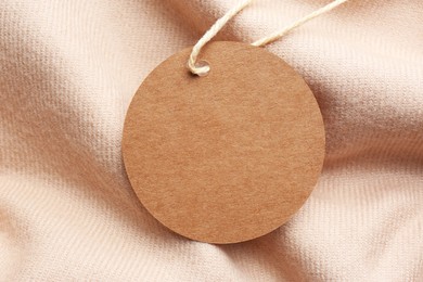Circle shaped tag with space for text on beige fabric, top view
