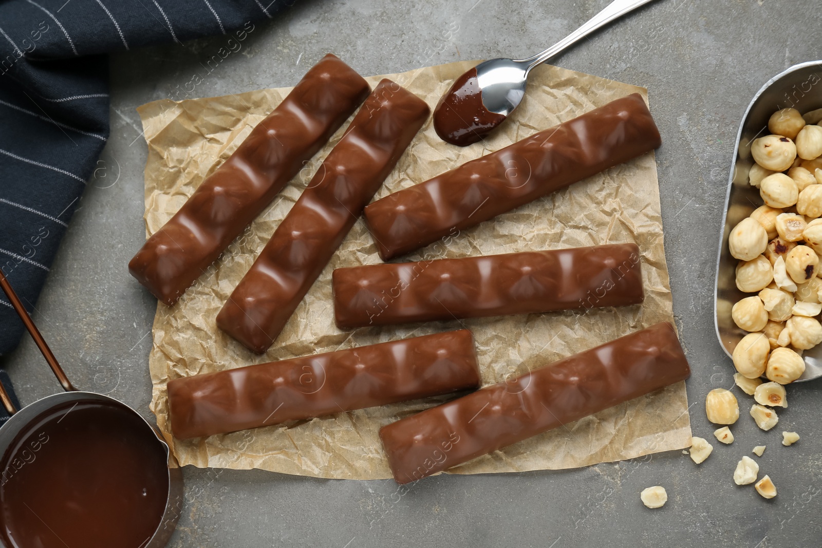 Photo of Tasty chocolate bars and nuts on grey table, flat lay