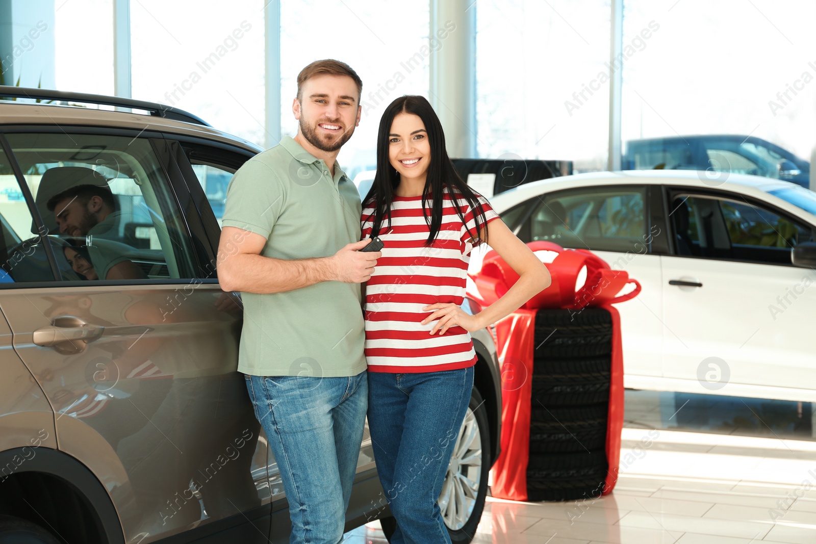 Photo of Happy couple with car key in modern auto dealership