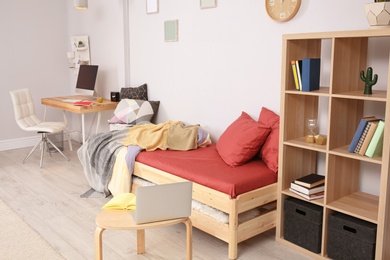 Photo of Comfortable bed and table with laptop in modern child room